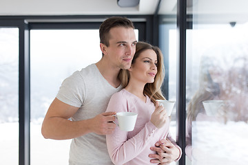 Image showing young couple enjoying morning coffee by the window