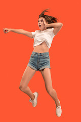 Image showing Freedom in moving. Pretty young woman jumping against orange background