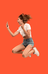 Image showing Full length of pretty young woman with mobile phone while jumping