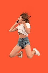 Image showing Full length of pretty young woman with mobile phone while jumping