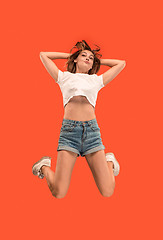 Image showing Freedom in moving. Pretty young woman jumping against orange background