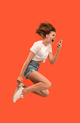 Image showing Full length of pretty young woman with mobile phone while jumping