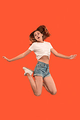 Image showing Freedom in moving. Pretty young woman jumping against orange background