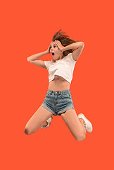 Image showing Freedom in moving. Pretty young woman jumping against orange background