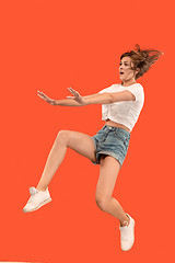 Image showing Freedom in moving. Pretty young woman jumping against orange background