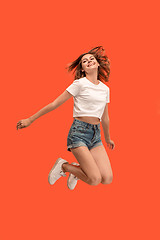 Image showing Freedom in moving. Pretty young woman jumping against orange background