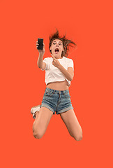 Image showing Full length of pretty young woman with mobile phone while jumping