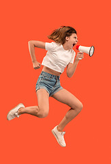 Image showing Beautiful young woman jumping with megaphone isolated over red background