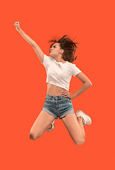 Image showing Freedom in moving. Pretty young woman jumping against orange background