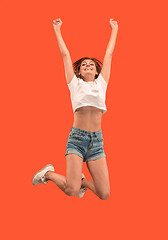 Image showing Freedom in moving. Pretty young woman jumping against orange background