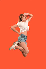 Image showing Freedom in moving. Pretty young woman jumping against orange background