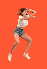 Image showing Freedom in moving. Pretty young woman jumping against orange background