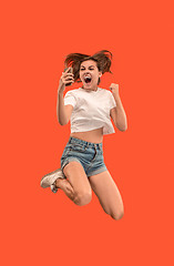 Image showing Full length of pretty young woman with mobile phone while jumping