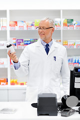 Image showing senior apothecary with drug at pharmacy