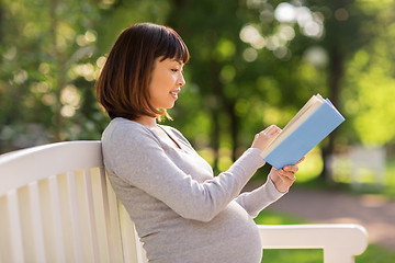 Image showing happy pregnant asian woman reading book at park