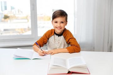 Image showing boy doing homework and writing to notebook at home