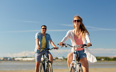 Image showing happy young couple riding bicycles at seaside