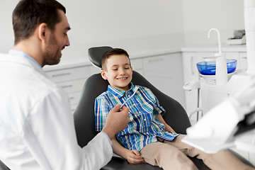 Image showing dentist giving toothbrush to kid patient at clinic