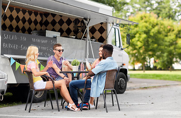 Image showing friends with drinks sitting at table at food truck