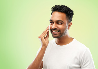 Image showing smiling indian man cleaning face with cotton pad