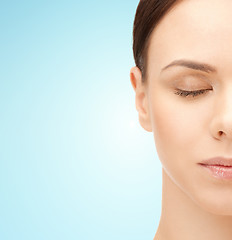 Image showing half face of young woman over blue background