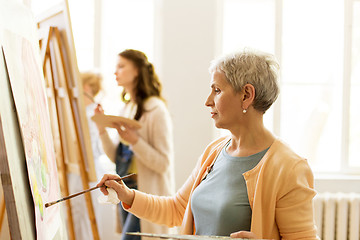 Image showing senior woman painting at art school studio