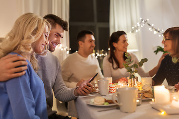 Image showing happy couple with smartphone at family tea party