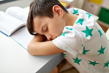 Image showing tired student boy sleeping on table at home