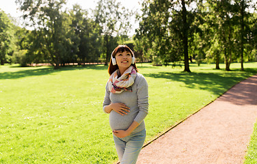 Image showing happy pregnant asian woman in headphones at park