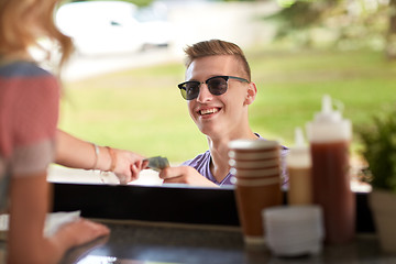 Image showing happy young man paying money at food truck