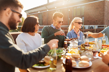 Image showing happy friends eating at barbecue party on rooftop