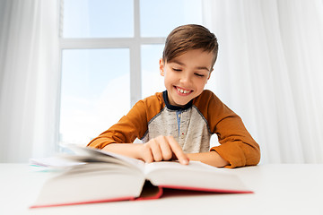 Image showing student boy reading book at home table