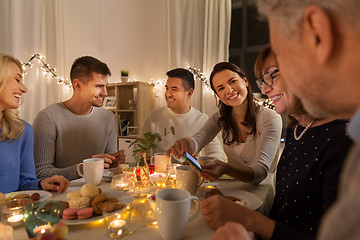 Image showing happy family with smartphone at tea party at home