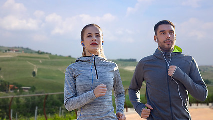 Image showing happy couple with earphones running outdoors