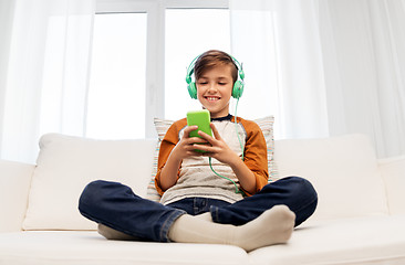 Image showing happy boy with smartphone and headphones at home