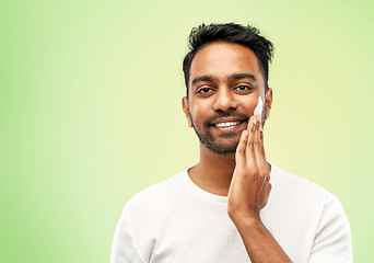 Image showing happy indian man applying cream to face