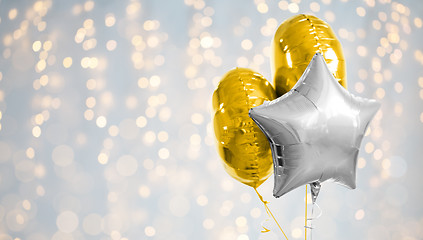 Image showing three gold and silver helium balloons on white