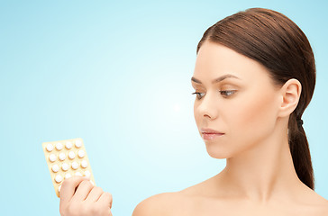 Image showing young woman with pills over blue background