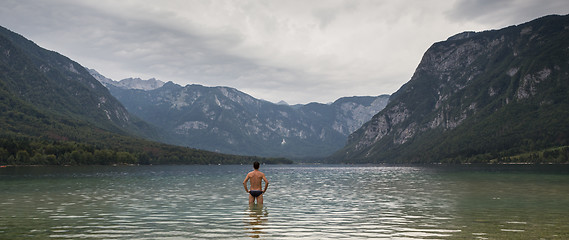 Image showing Man going to swim in freezing cold lake Bohinj, Alps mountains, Slovenia, on tranquil overcast morning