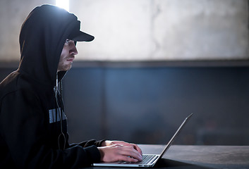 Image showing talented hacker using laptop computer while working in dark offi