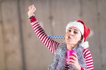 Image showing young business woman wearing a red hat and blowing party whistle