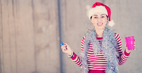 Image showing young business woman wearing a red hat and blowing party whistle