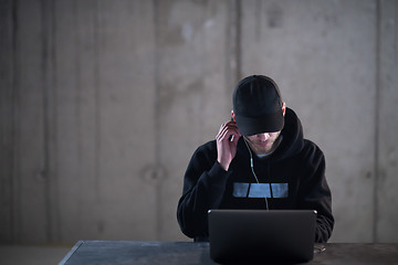 Image showing talented hacker using laptop computer while working in dark offi