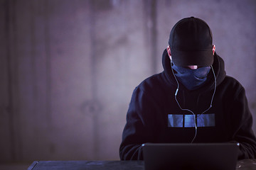 Image showing talented hacker using laptop computer while working in dark offi