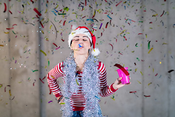 Image showing business woman wearing a red hat and blowing party whistle