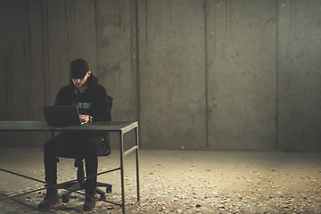 Image showing talented hacker using laptop computer while working in dark offi