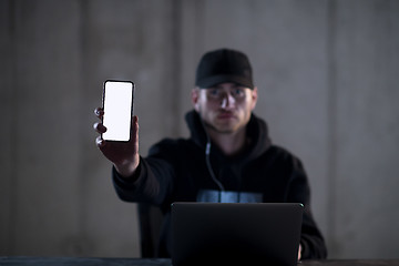 Image showing criminal hacker using laptop computer while working in dark offi