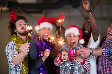 Image showing multiethnic group of casual business people lighting a sparkler