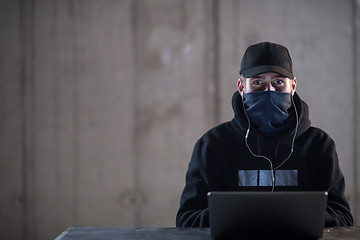 Image showing talented hacker using laptop computer while working in dark offi