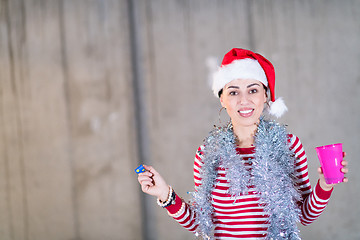 Image showing young business woman wearing a red hat and blowing party whistle